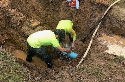 Two utility workers fixing a water main leak