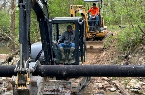 Two utility workers laying a water main line